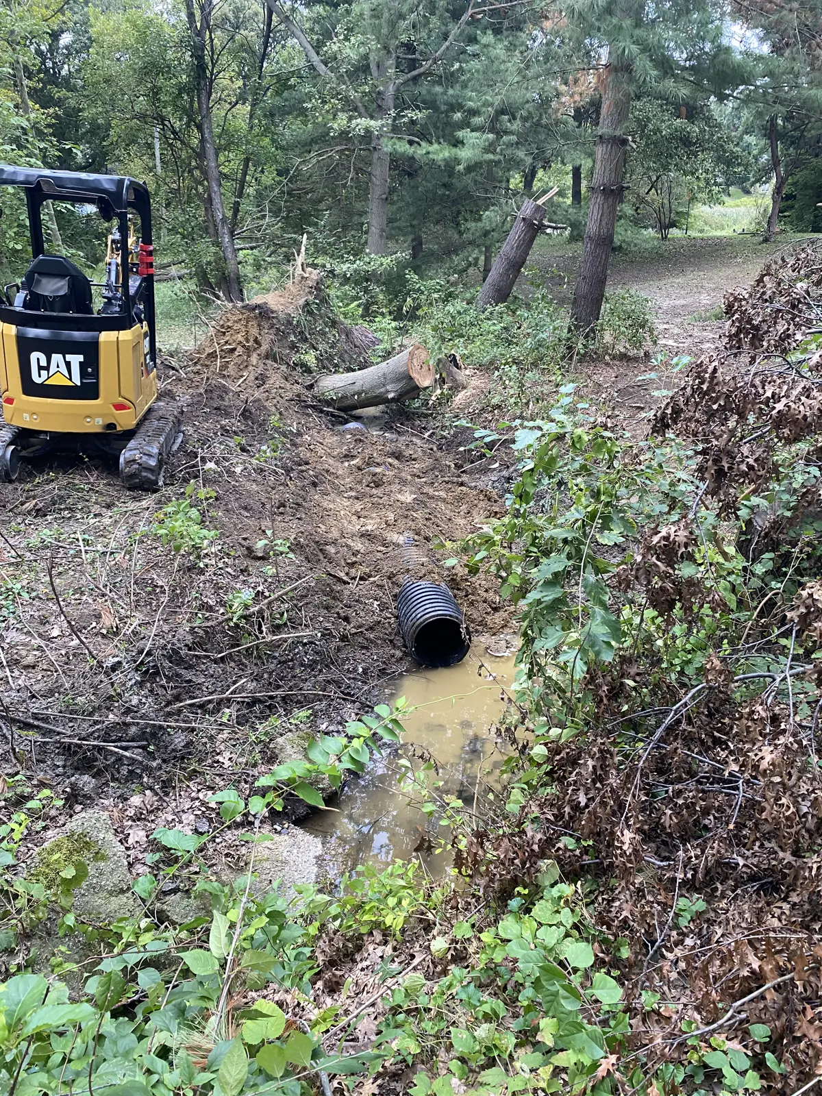 Corrugated culvert pipe set in the ditch with the excavator on the bank