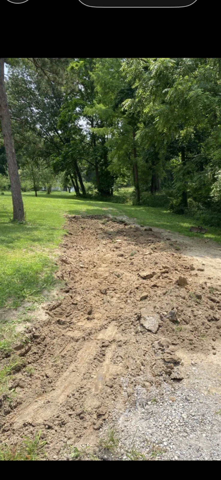 Freshly excavated strip of earth along a gravel drive and lawn
